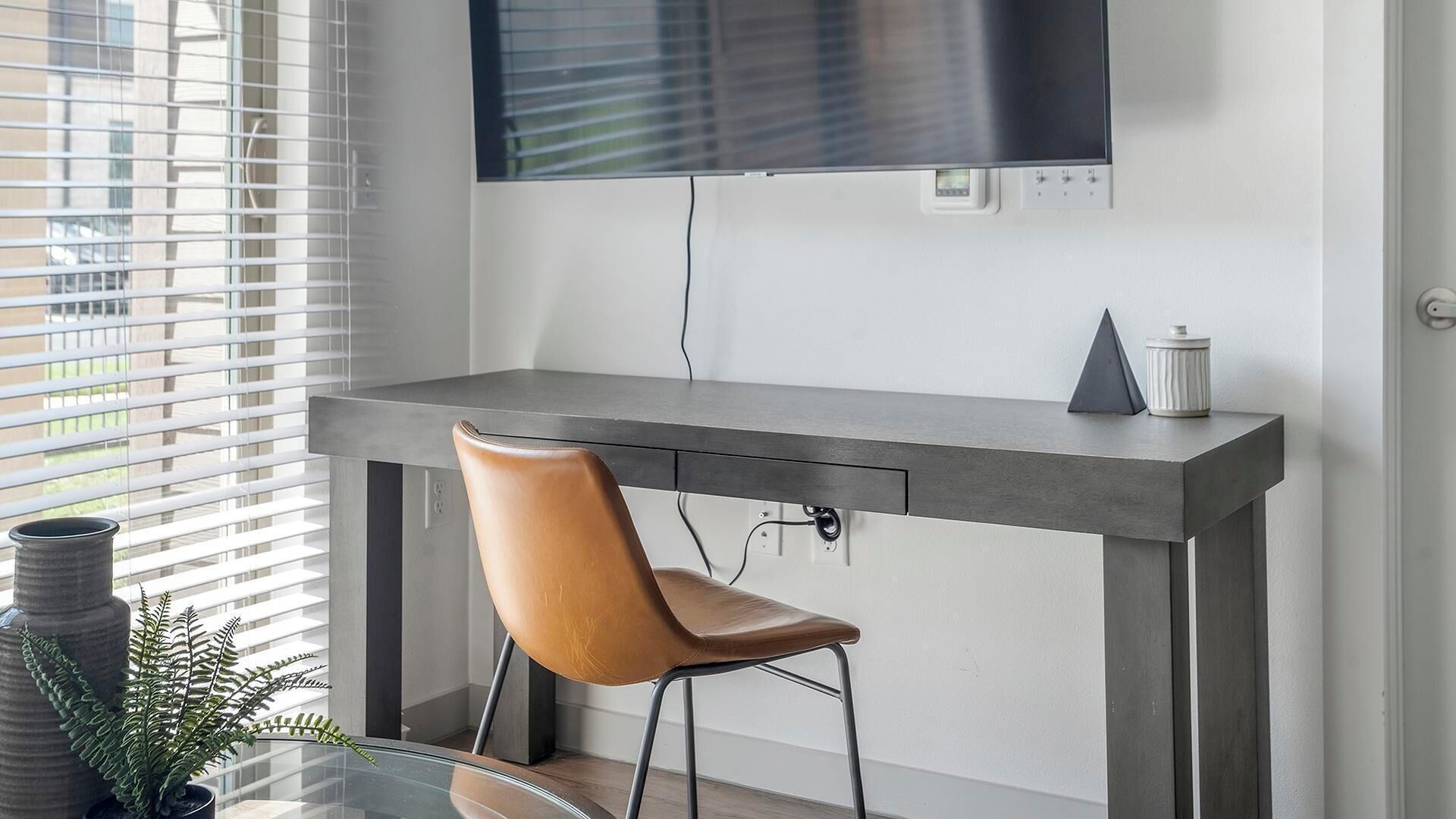 A modern kitchen with a built-in TV, a grey countertop, and a brown chair.