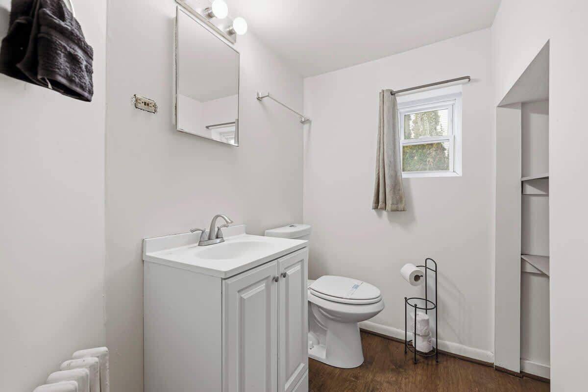 Ein modernes Badezimmer mit Waschbecken, Toilette und Spiegel, alles in Weiß.