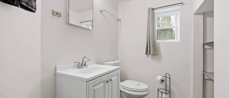 Ein modernes Badezimmer mit Waschbecken, Toilette und Spiegel, alles in Weiß.