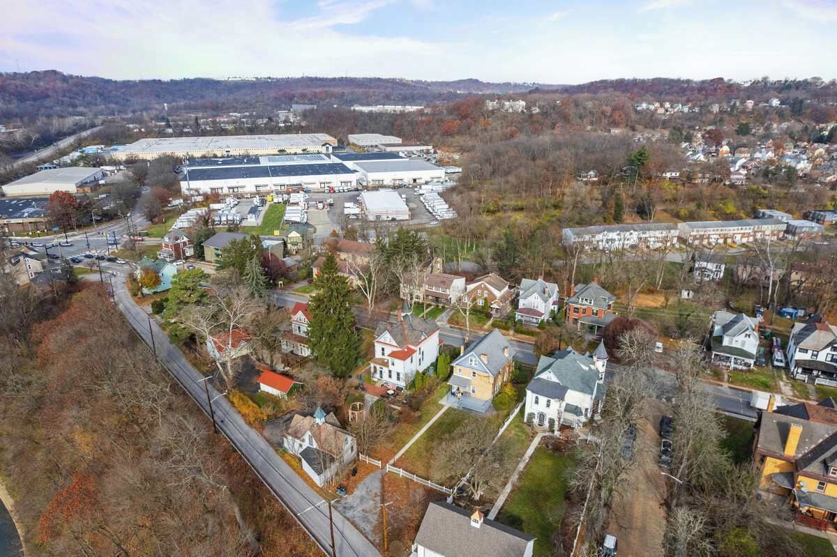 An aerial view of a town with a large industrial building, residential houses, and a railway track.