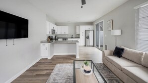 A modern kitchen with white cabinets, a granite countertop, and a stainless steel refrigerator. - Landing | Stylish 1BD, Gym, Pool (Madison)