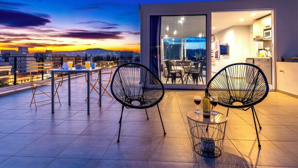 A rooftop terrace with two chairs and a table, a bottle of wine, and a glass. - Acropolis Magical View Suite, Metro Kerameikos (Athens)