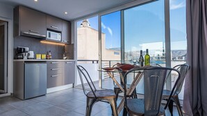 A modern kitchen with a dining area, large windows, and a view of the city. - Acropolis Magical View Suite, Metro Kerameikos (Athens)