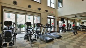 Un gimnasio con cintas de correr, elípticas y pesas libres.