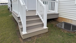 Ein zweistöckiges Haus mit Veranda und kleiner Terrasse.