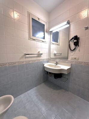 Een badkamer met een wastafel, spiegel en raam.