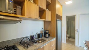 Una cocina moderna con armarios de madera, un refrigerador de acero inoxidable, una cafetera y un escurreplatos.
