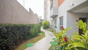 Un sendero estrecho bordeado por follaje y un edificio de fachada moderna.