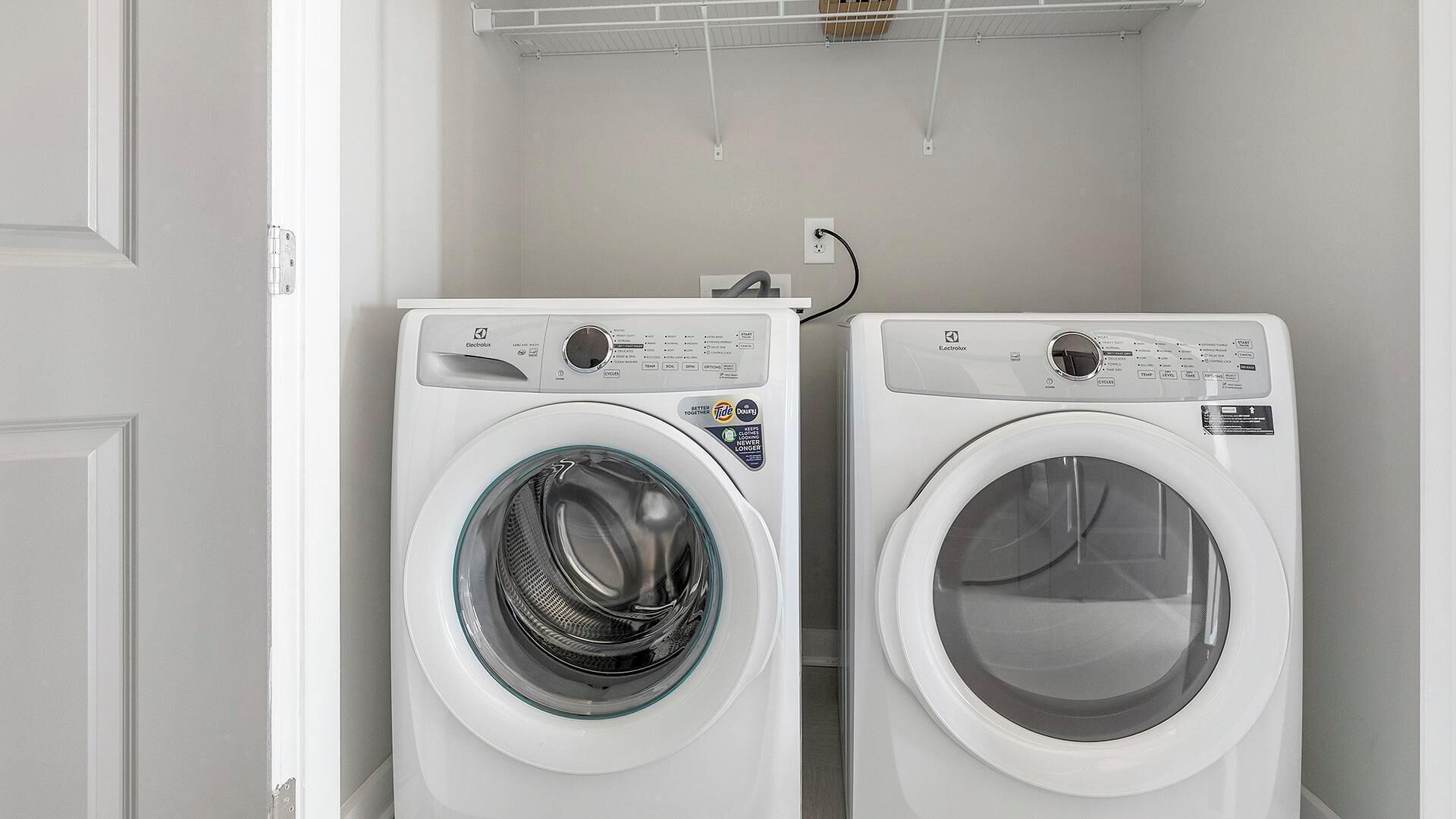 Due lavatrici bianche a carica frontale in una lavanderia con una porta bianca e un soffitto bianco.
