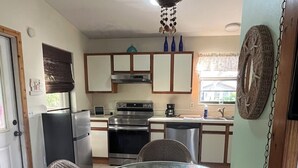 A compact kitchen with a dining area, including a round glass table with chairs, a refrigerator, an oven, and a coffee maker. - Fisherman's Paradise!  50' Concrete Dock. Space for 2 boats (Big Pine Key)