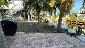 A patio area with a brick floor, a grill, and a small pond. - Fisherman's Paradise!  50' Concrete Dock. Space for 2 boats (Big Pine Key)
