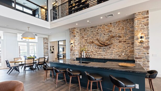 Eine moderne Küche mit Steinrückwand, einer Bar und hohen Decken mit einem Balkon.