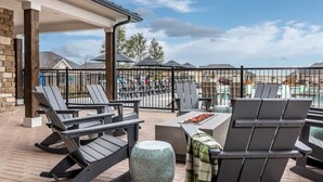 Eine Terrasse im Freien mit Liegestühlen, einem Steintisch und einem Grill.