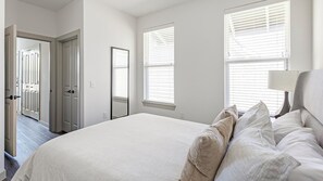 Un dormitorio con cama, mesita de noche y ventana con persianas.