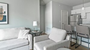 Ein modernes Wohnzimmer mit einem grauen Sofa, einem kleinen Beistelltisch und einer Lampe.