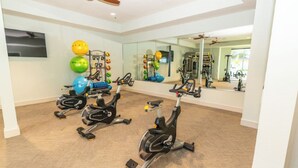 Ein Heimfitnessraum mit Ergometer, Gymbällen und einem Spiegel, der Trainingsgeräte reflektiert.