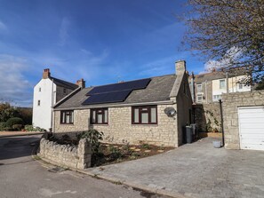 Ein Steinhaus mit geneigtem Dach, Solaranlage und Garage.