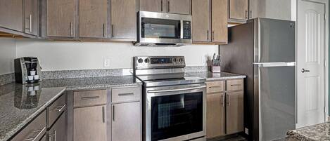 A modern kitchen with stainless steel appliances, wooden cabinets, and granite countertops.