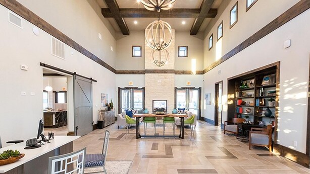 A spacious dining area with a central table and chairs, a chandelier, and a bookshelf filled with books and decorative items. - Landing | Amazing 1BD, Clubhouse, Gym (Manor)