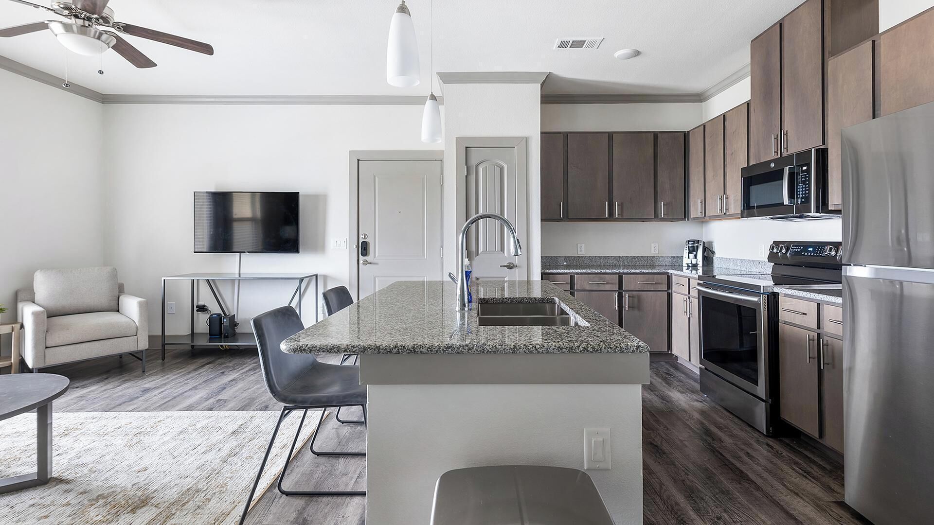 A modern kitchen with granite countertops, stainless steel appliances, and wooden cabinets.