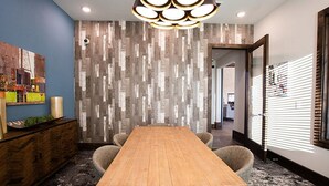 A conference room with a wooden table, chairs, a modern light fixture, a decorative wall, and a window with blinds. - Landing | Amazing 1BD, Clubhouse, Gym (Manor)