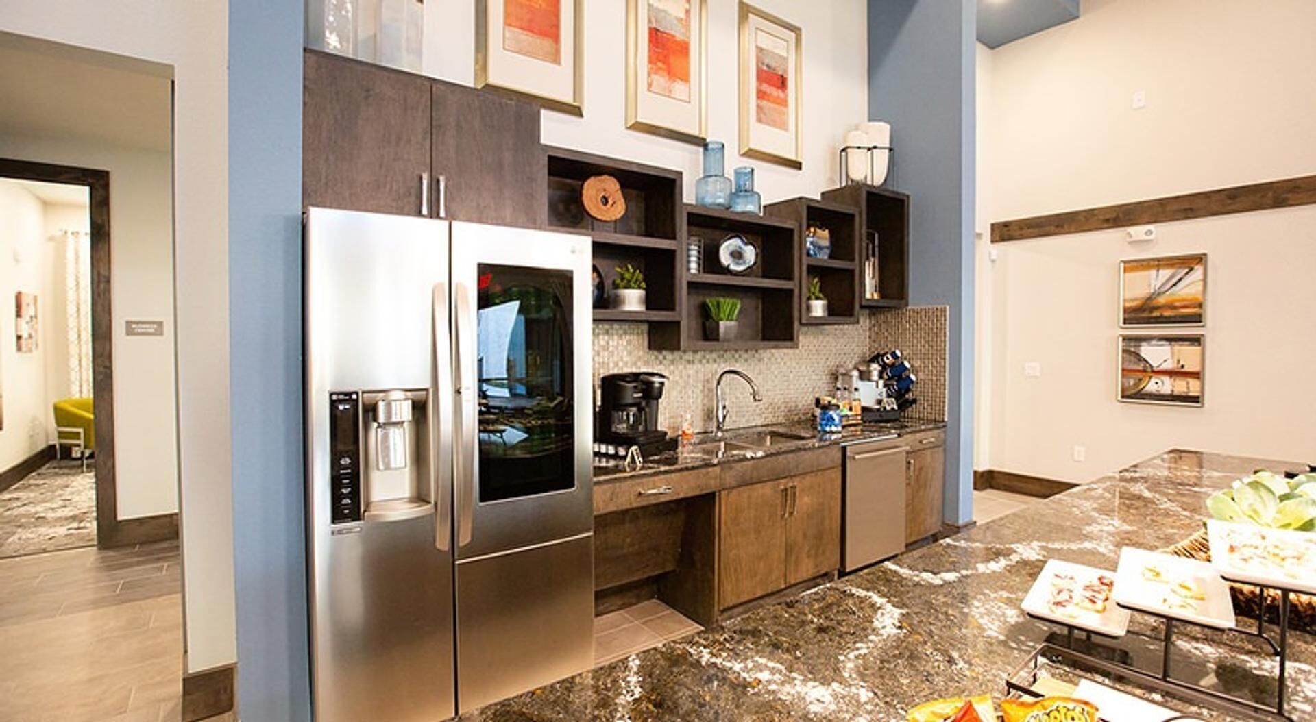 A modern kitchen with stainless steel appliances, a marble countertop, and a dining area with a buffet setup.