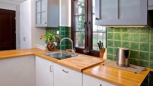 A kitchen with white cabinets, a wooden countertop, a sink, and a window with a view of greenery. - Comfortable holiday home, pool, sauna, jacuzzi (Sasino)