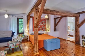 Una habitación con una cama, una silla, una mesita y una estantería.