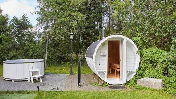 A small, white, semi-circular structure with an open door, a bench, and a hot tub in the background. - Comfortable holiday home, pool, sauna, jacuzzi (Sasino)