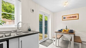 Una cocina con ventana, un fregadero y una zona de comedor con mesa y banco.