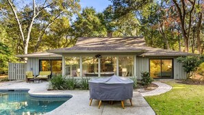 Ein Haus mit Pool, überdachter Terrasse und Rasenfläche.