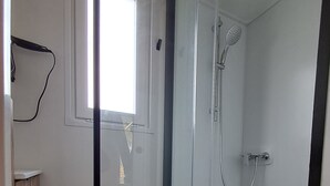A glass-enclosed shower room with a window, a towel rack, and a wooden floor. - Suite Hôtel (Le Temple-sur-Lot)