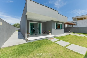 A modern two-story house with a covered patio, a well-maintained lawn, and a clear sky. - House w/ Grill in Front of the Beach Lbra0011 (Ilhéus)
