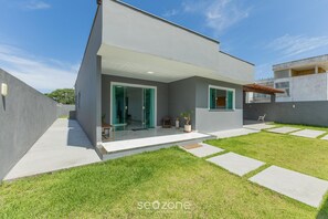 A modern two-story house with a covered patio, a well-maintained lawn, and a clear sky. - House w/ Grill in Front of the Beach Lbra0011 (Ilhéus)