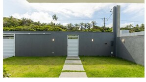 A modern outdoor area with a concrete wall, a white door, and a pathway leading to a covered space. - House w/ Grill in Front of the Beach Lbra0011 (Ilhéus)