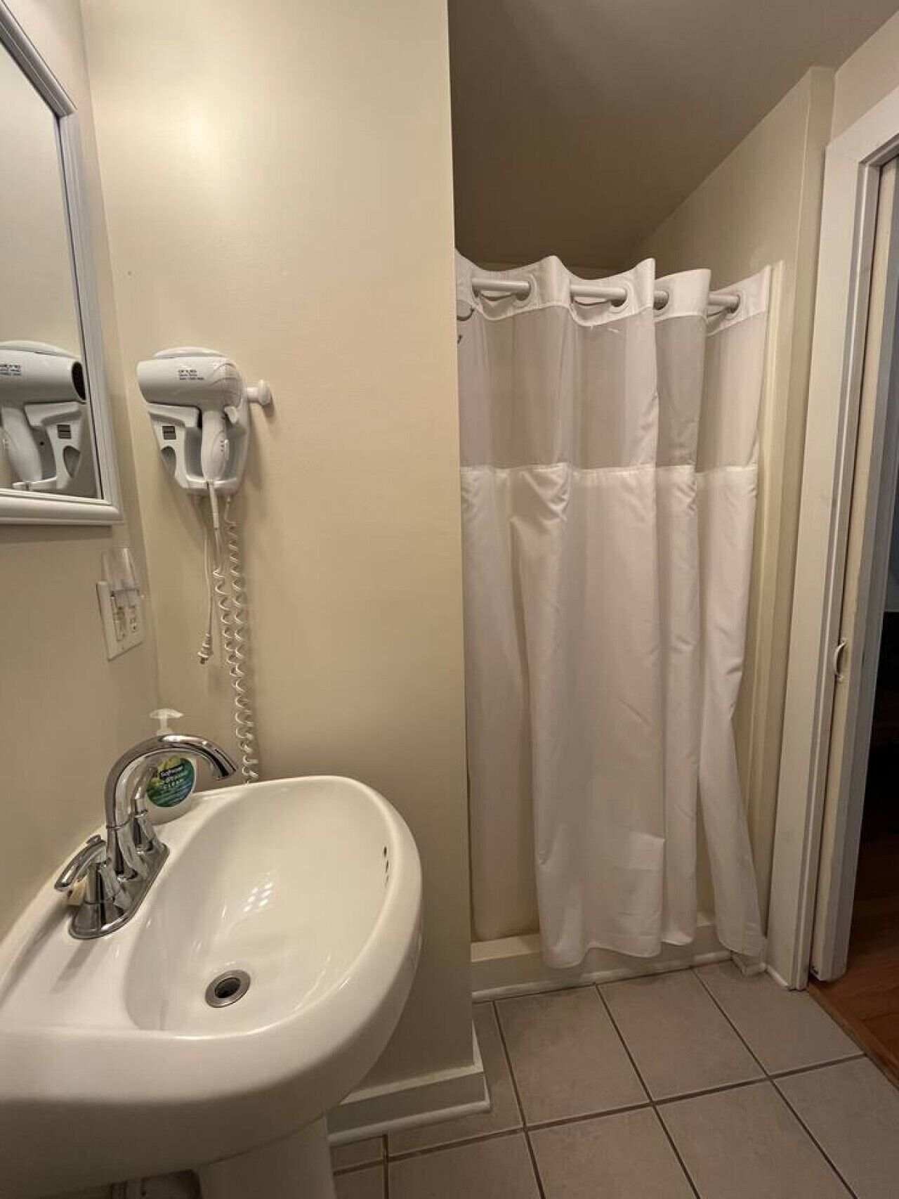 Casa de banho com lavatório, secador de cabelo e cortina de chuveiro.