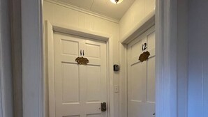 A hallway with white doors, a wooden floor, and a ceiling light fixture. - Gulf Stream House - Unit 12 (Hammondsport)