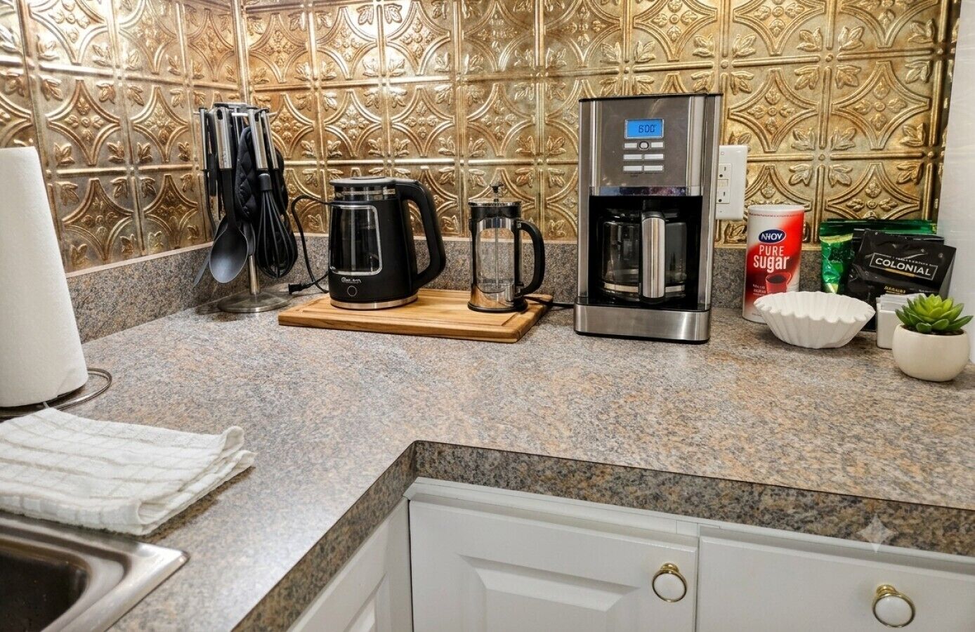 A kitchen with a coffee maker, kettle, and sugar canister.