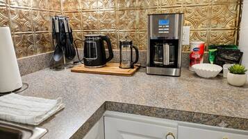 A kitchen with a coffee maker, kettle, and sugar canister.