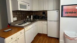 A compact kitchen with white cabinets, a microwave, a refrigerator, and a wooden countertop. - Gulf Stream House - Unit 12 (Hammondsport)