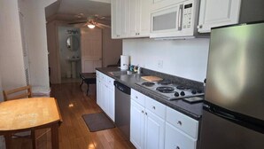 A kitchen with white cabinets, a stainless steel refrigerator, a microwave, and a stove. - Gulf Stream House - Unit 11 (Hammondsport)