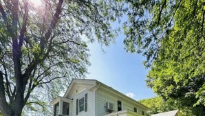 A two-story building with a porch and a flag. - Gulf Stream House - Unit 11 (Hammondsport)