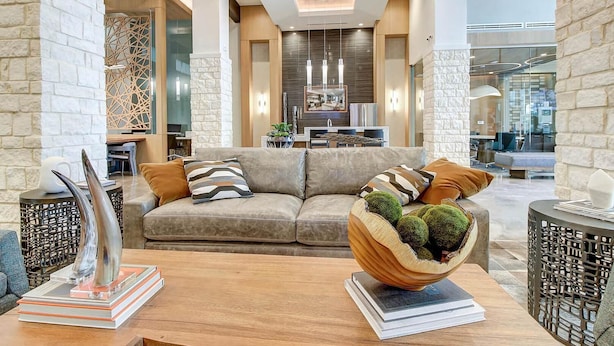 A modern living room with a sofa, decorative pillows, a wooden coffee table, and a unique spherical plant holder. - Landing | Beautiful 2BD, Pool, Clubhouse (San Antonio)