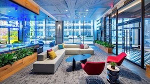 A modern lounge area with a large sectional sofa, red chairs, and a coffee table. - Landing | Incredible 1BD, Gym, Game Room (Arlington)
