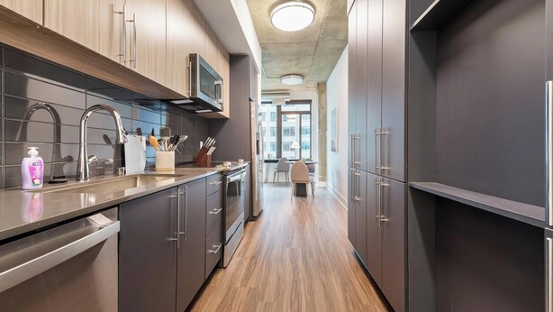 A modern kitchen with stainless steel appliances, wooden cabinets, and a central island. - Landing | Incredible 1BD, Gym, Game Room (Arlington)