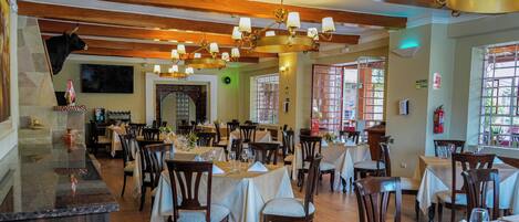 Un restaurante con suelos de madera, varias mesas y sillas, una zona de bar y una decoración de cabeza de toro en la pared.