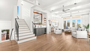 Ein geräumiger Wohnbereich mit Treppe, einer Küche und einer Sitzecke inklusive Sofa und Couchtisch.