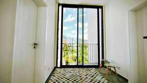 Een modern appartement met een grote schuifglazen deur die leidt naar een balkon met uitzicht op de stad.