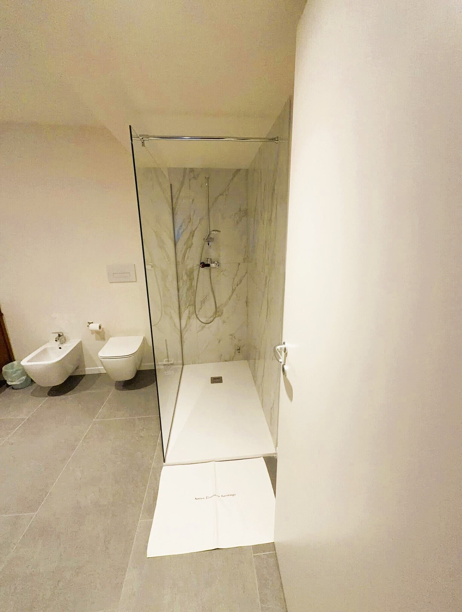 A modern bathroom with a glass-enclosed shower, a bidet, and a toilet.