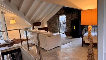 Amplio dormitorio tipo loft con pared de piedra, chimenea y ventana grande que da a un balcón.
